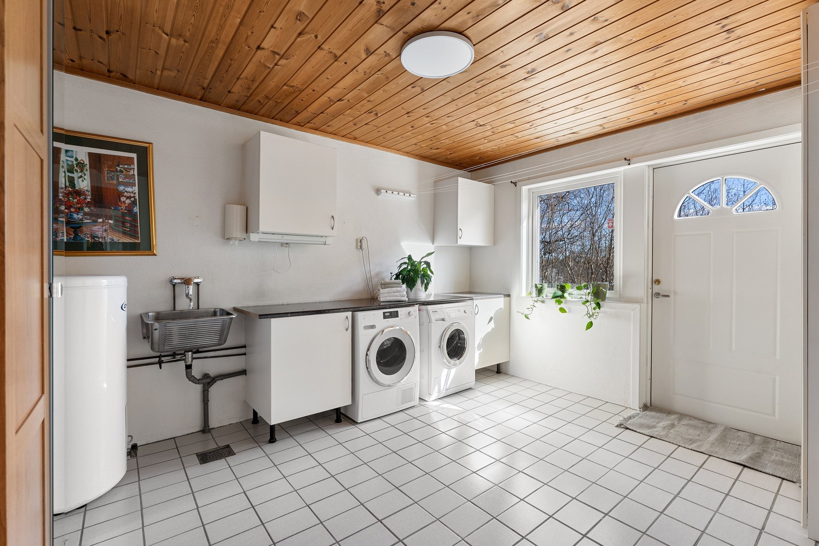 Praktisk vaskerom i underetasjen med egen inngang, flislagt gulv med varme og opplegg for vaskemaskin. Galleribilde