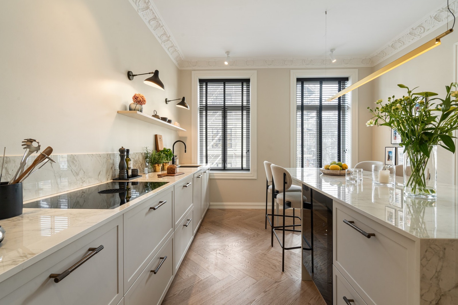 Store vindusflater slipper inn godt med naturlig lys, og sammen med god takhøyde og klassiske detaljer som stukkatur, oppleves rommet som både elegant og innbydende. Galleribilde