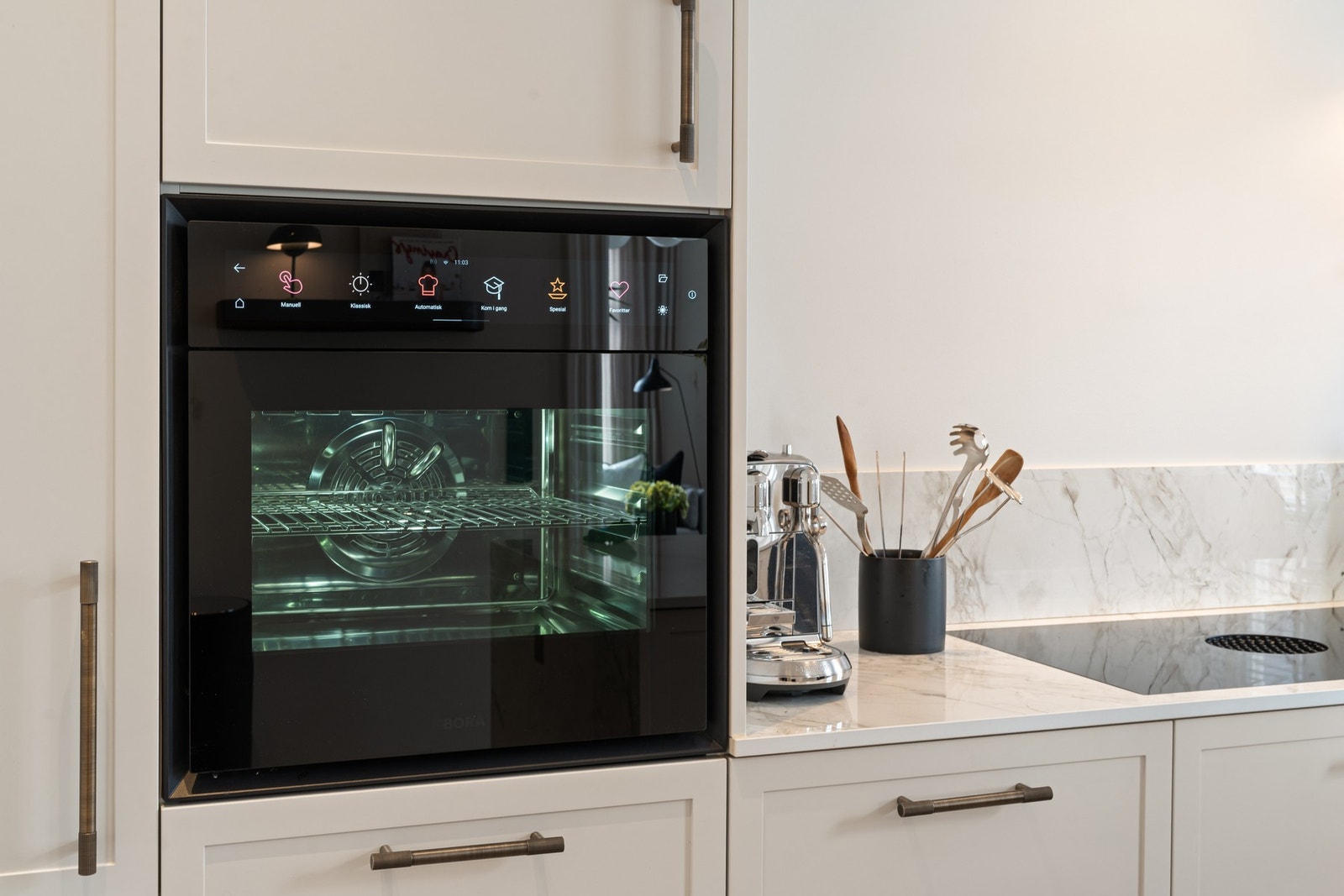 Kjøkkenet har integrerte hvitevarer, herunder kjøl/frys, stekeovn, oppvaskmaskin, vinskap samt platetopp med integrert ventilator, som gir et helhetlig og moderne uttrykk. Galleribilde