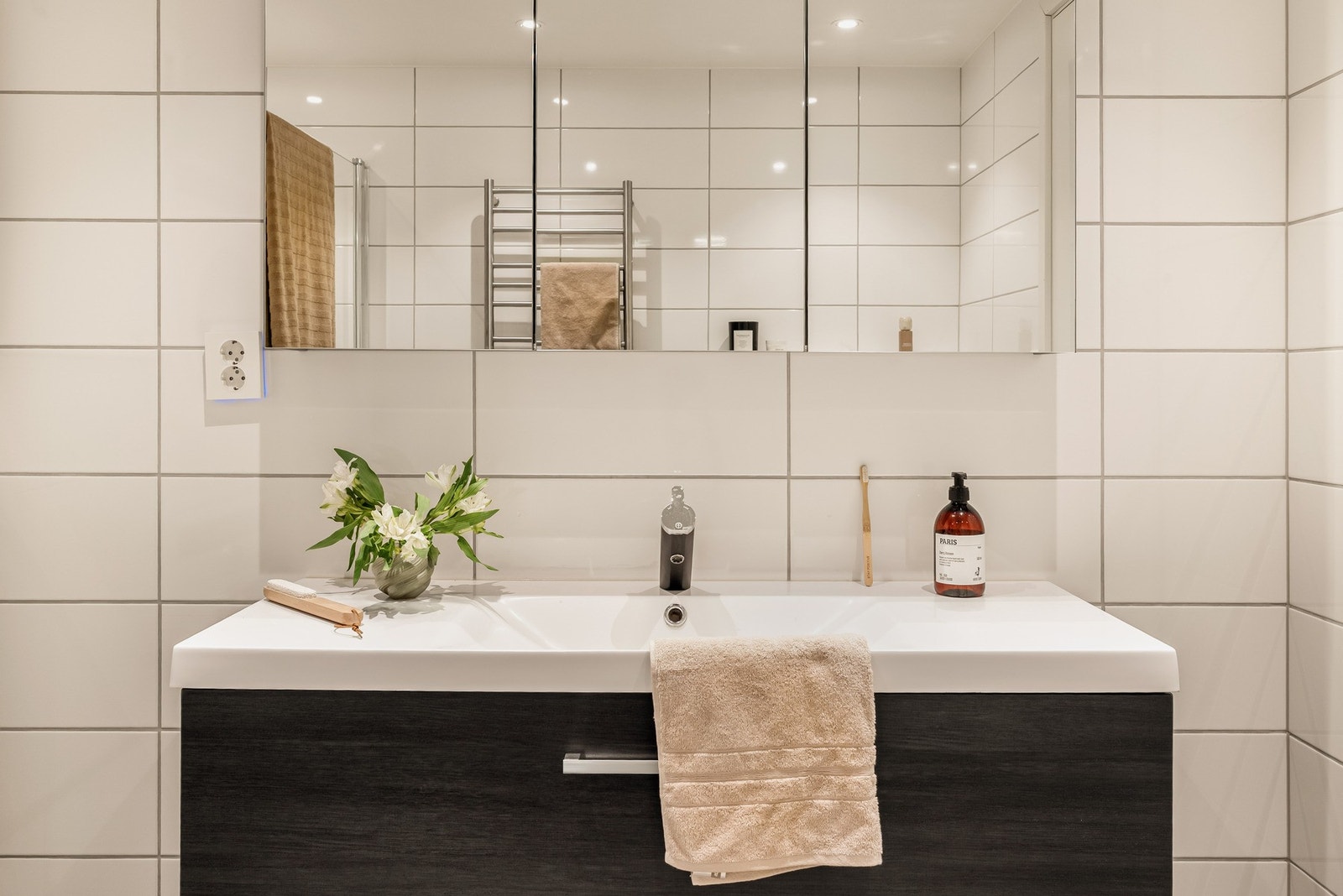 Badet inneholder dusjnisje med glassdør, vegghengt toalett og baderomsinnredning og speil. Galleribilde