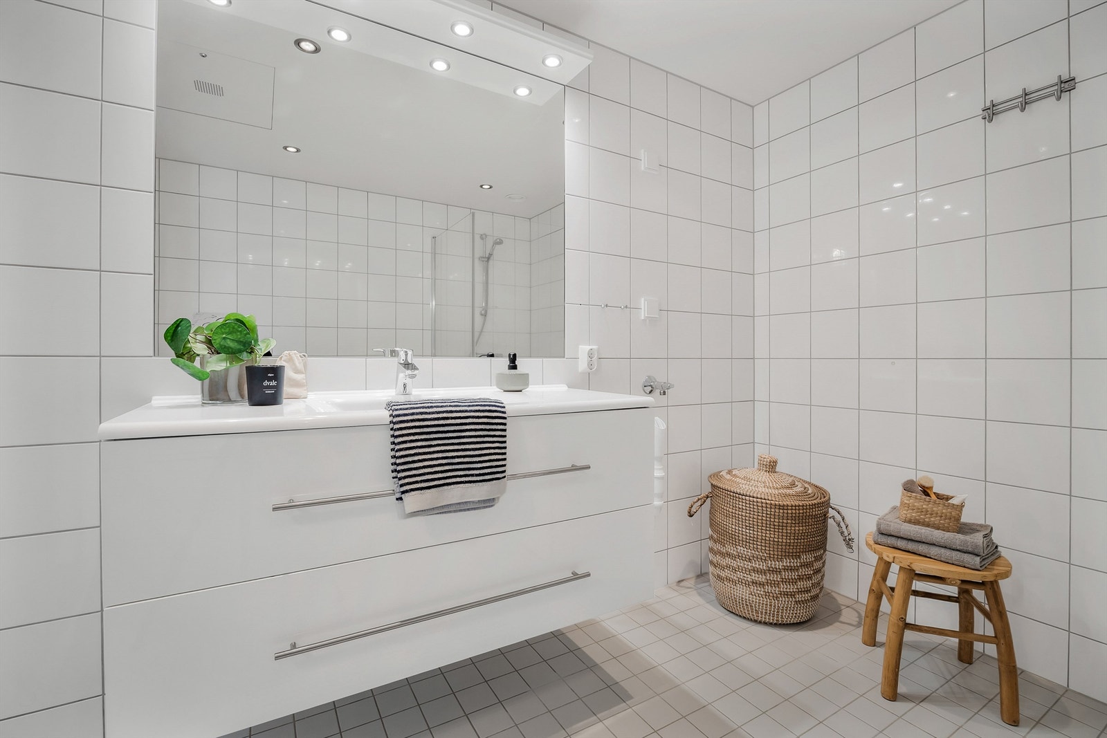 Badet har dusjhjørne med foldedører av glass og opplegg for vaskemaskin. Galleribilde