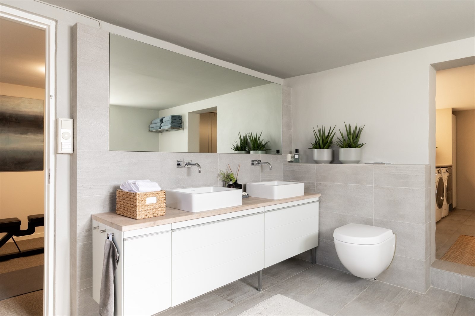 Badet er innredet med baderomsinnredning med to servanter og stort speil, integrert badekar, veggmontert toalett og dusjhjørne med mosaikkfliser. Galleribilde