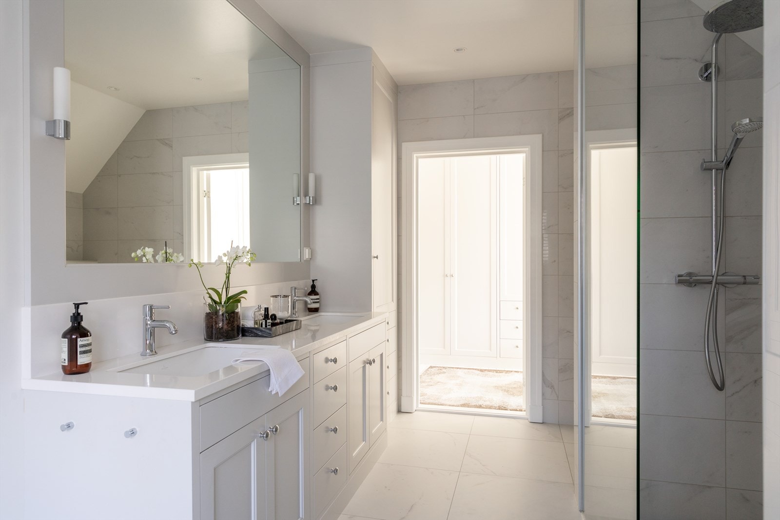 Badet har plassbygd innredning og speil av JH Interiør, med 3 cm benkeplate med splashback i Silestone levert av Nerostein, og to underlimte servanter. Galleribilde