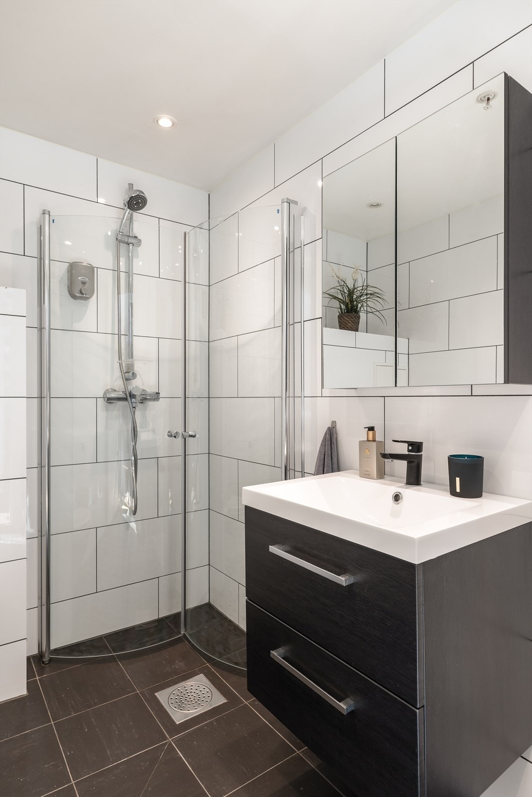 Badet er utstyrt med veggmontert WC, dusjhjørne med inn- og utadslående glassdører, servant med ettgreps blandebatteri i innredning med gode oppbevaringsmuligheter. Galleribilde