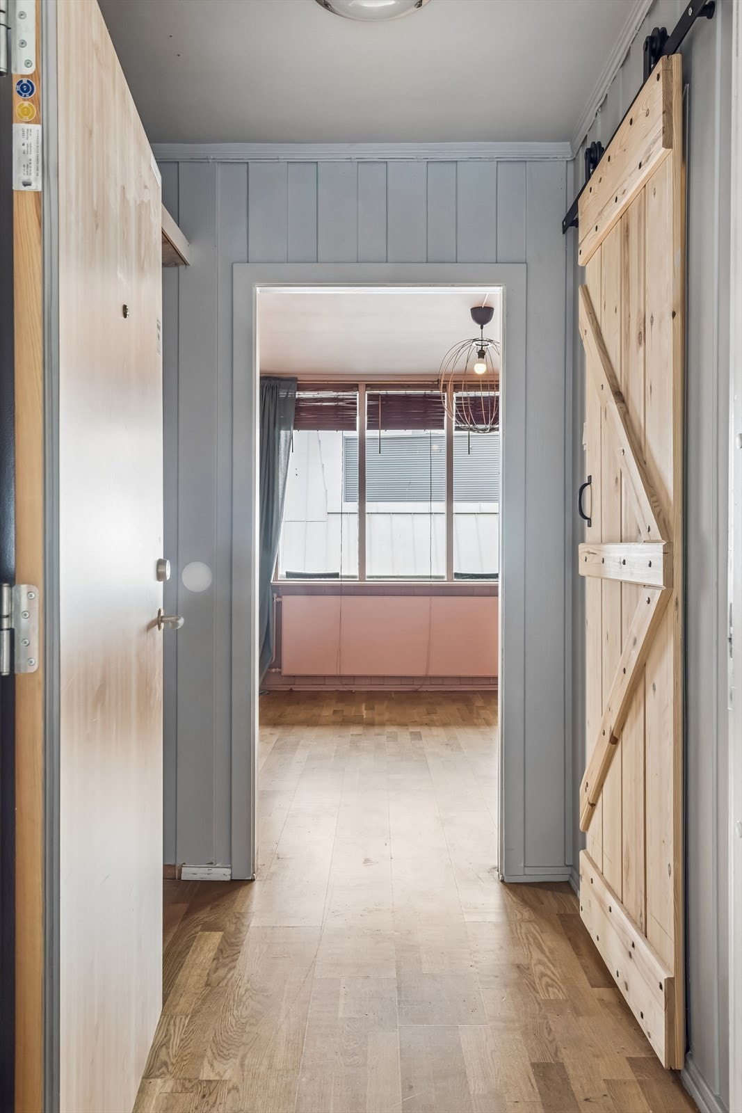 Entréen binder sammen leiligheten. Herfra er det adkomst til bad via en plassbesparende skyvedør i heltre. Galleribilde