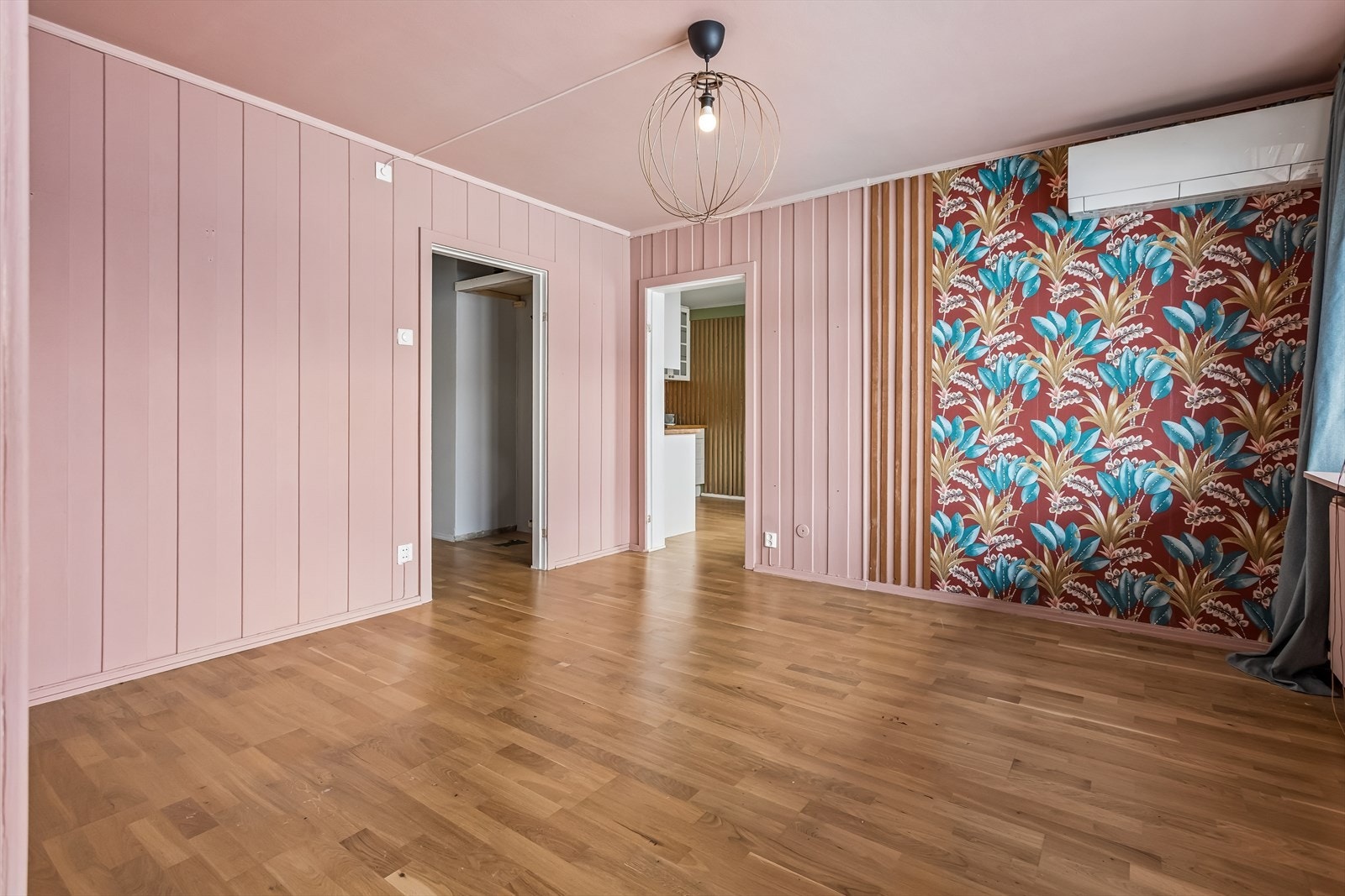 Stuen har parkett på gulv og en kombinasjon av malt trepanel, tapet og spilefelt på veggene. Galleribilde