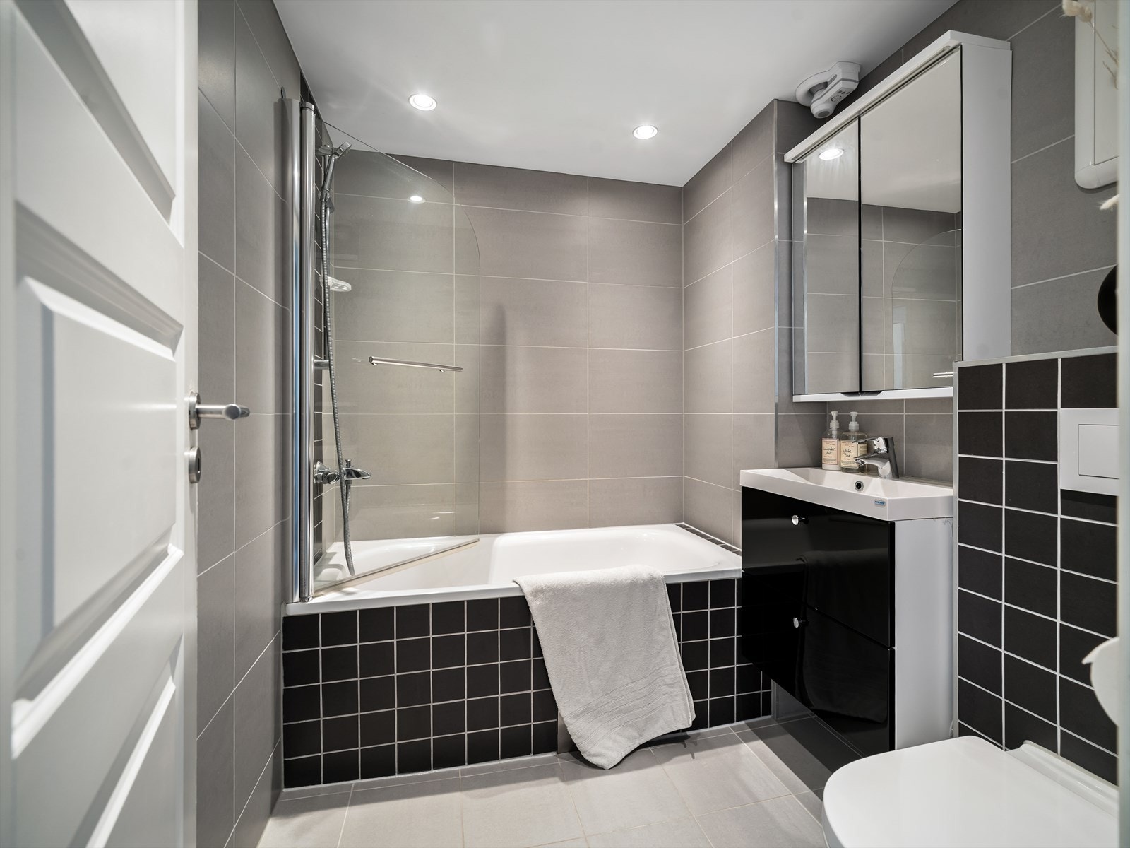 Badet er innredet med plassbygd badekar med dusjløsning, servantskap med nedfelt servant, vegghengt toalett og speilskap. Galleribilde