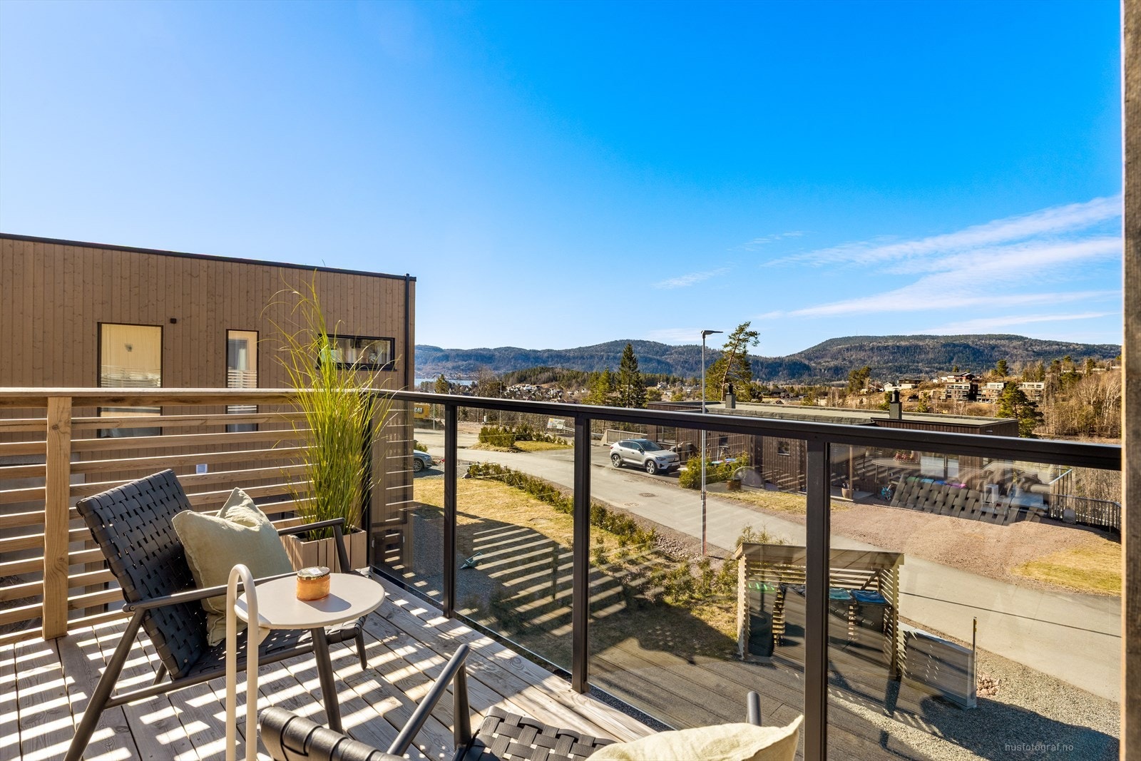 Moderne terrasse med glassrekkverk, solrik utsikt mot naturskjønne omgivelser. Galleribilde