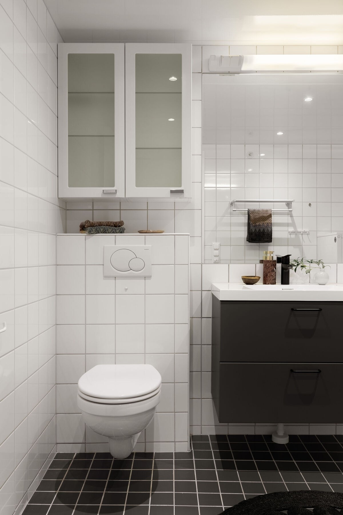 Baderomsinnredningen består av servant med heldekkende vask og oppbevaringsplass i underskap, speil med belysning, veggmontert toalett og opplegg for vaskemaskin. Galleribilde