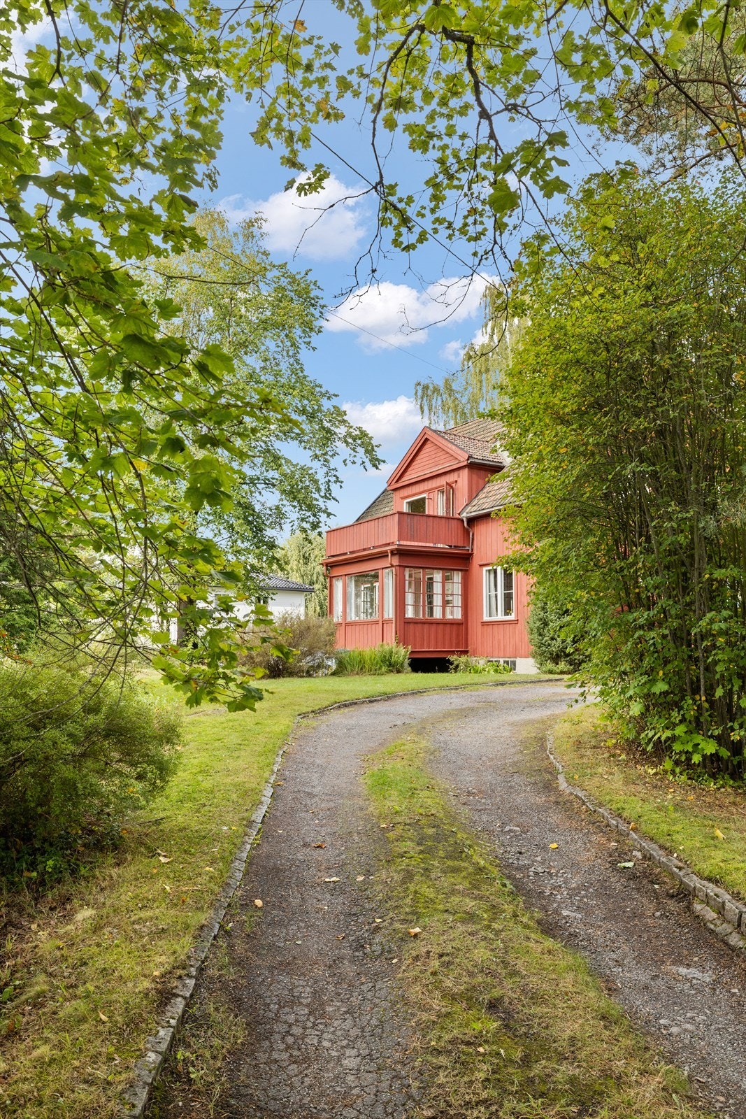 Eiendommen ligger skjermet fra veien, omgitt av frodig vegetasjon. Galleribilde