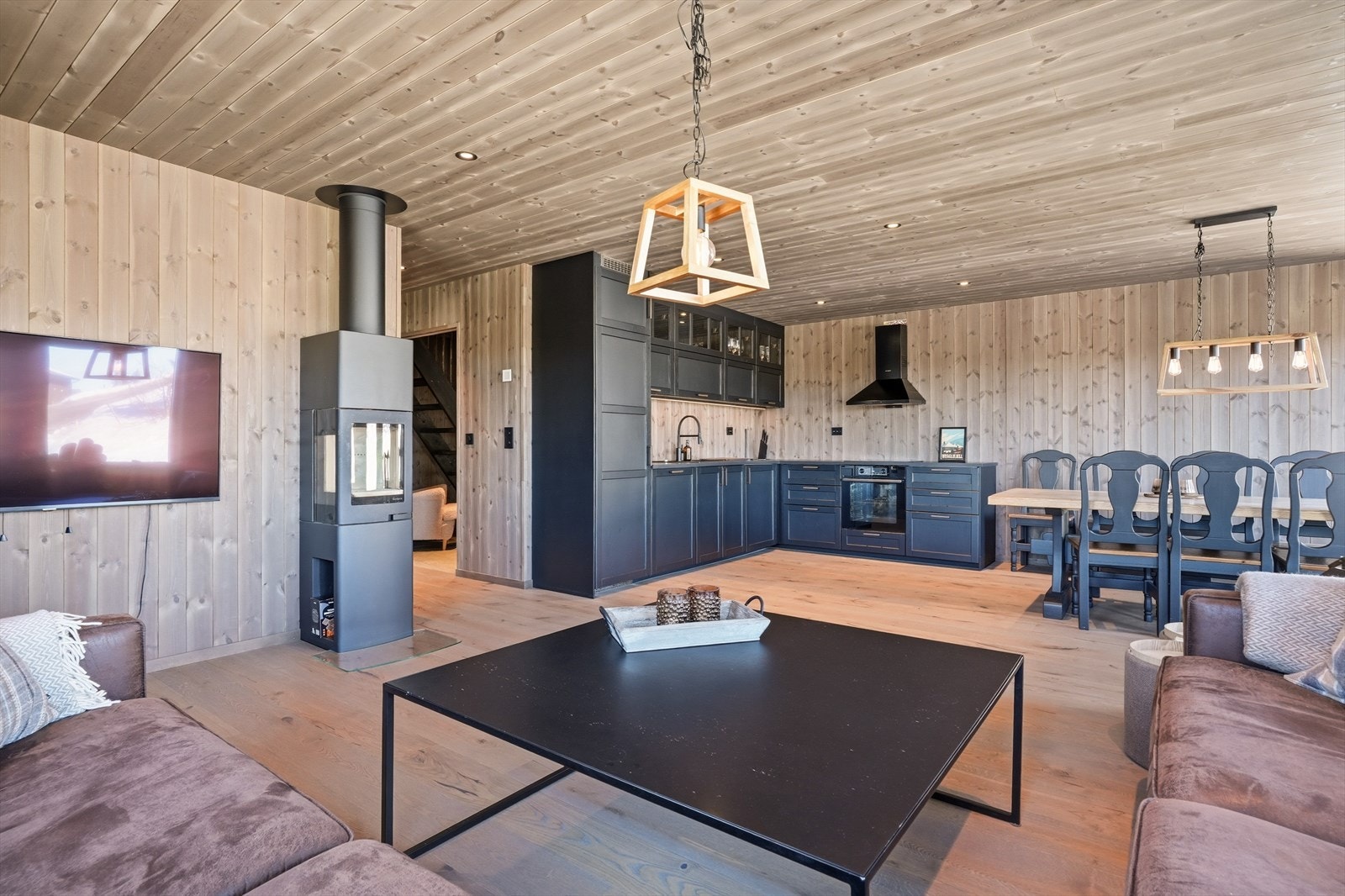 Hytta har en åpen og romslig løsning for stue og kjøkken, preget av lune og stilfulle farger og materialer. Galleribilde