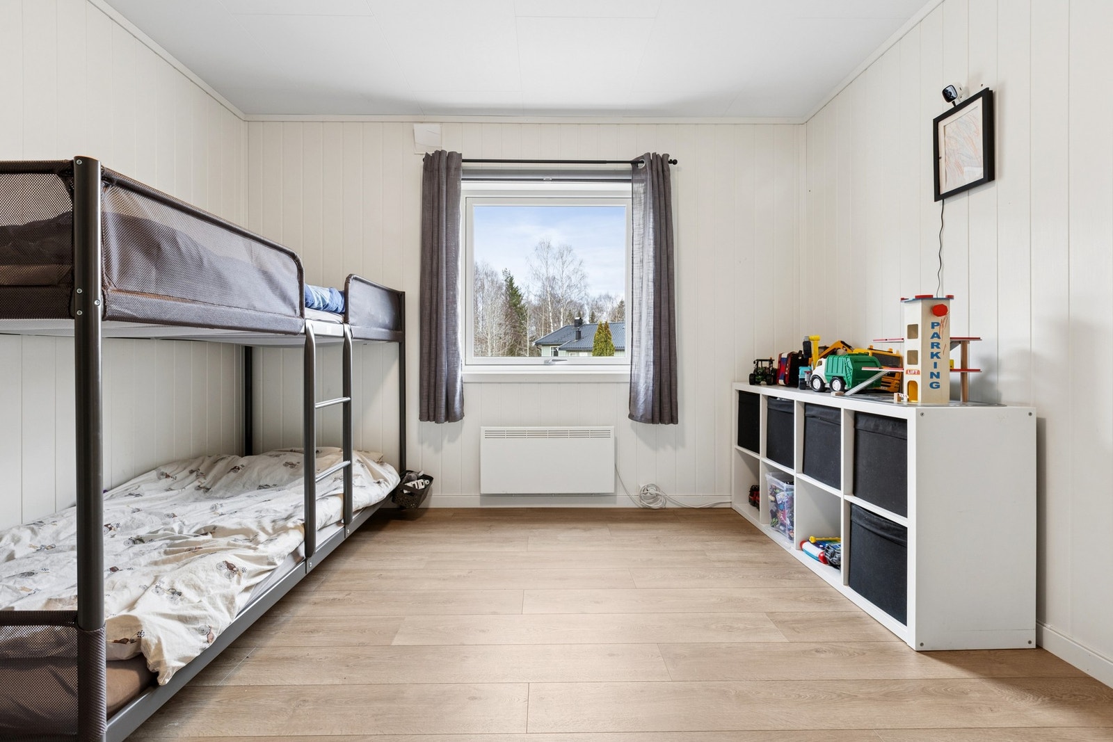 Lyst og romslig barnerom med plass til køyeseng og god plass til lek. Hyller med oppbevaring holder orden på leker, og vinduet gir med godt dagslys. Galleribilde