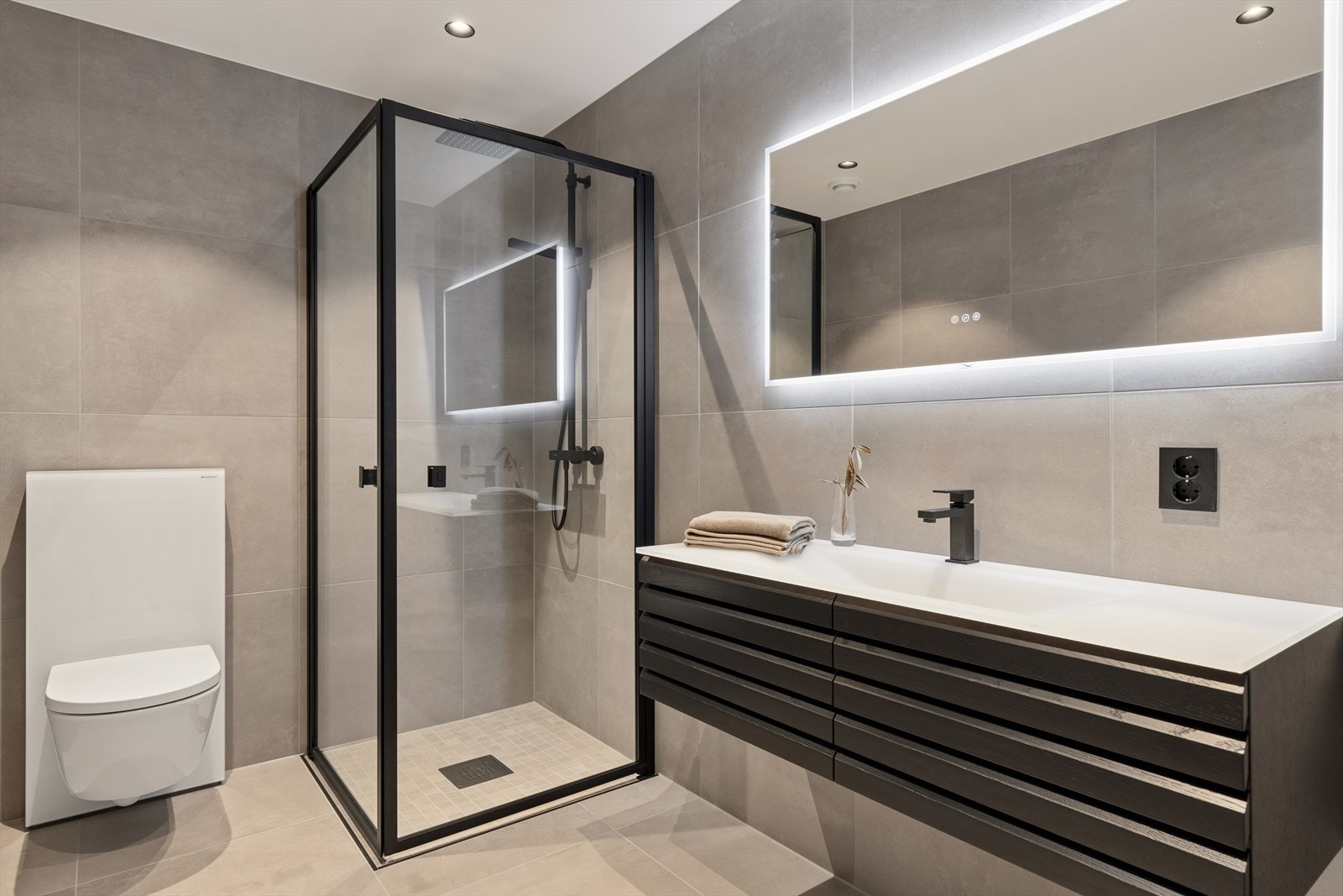 Badet fremstår som moderne og elegant, med lyse fliser på både vegger og gulv som gir et rent og tidløst uttrykk Galleribilde