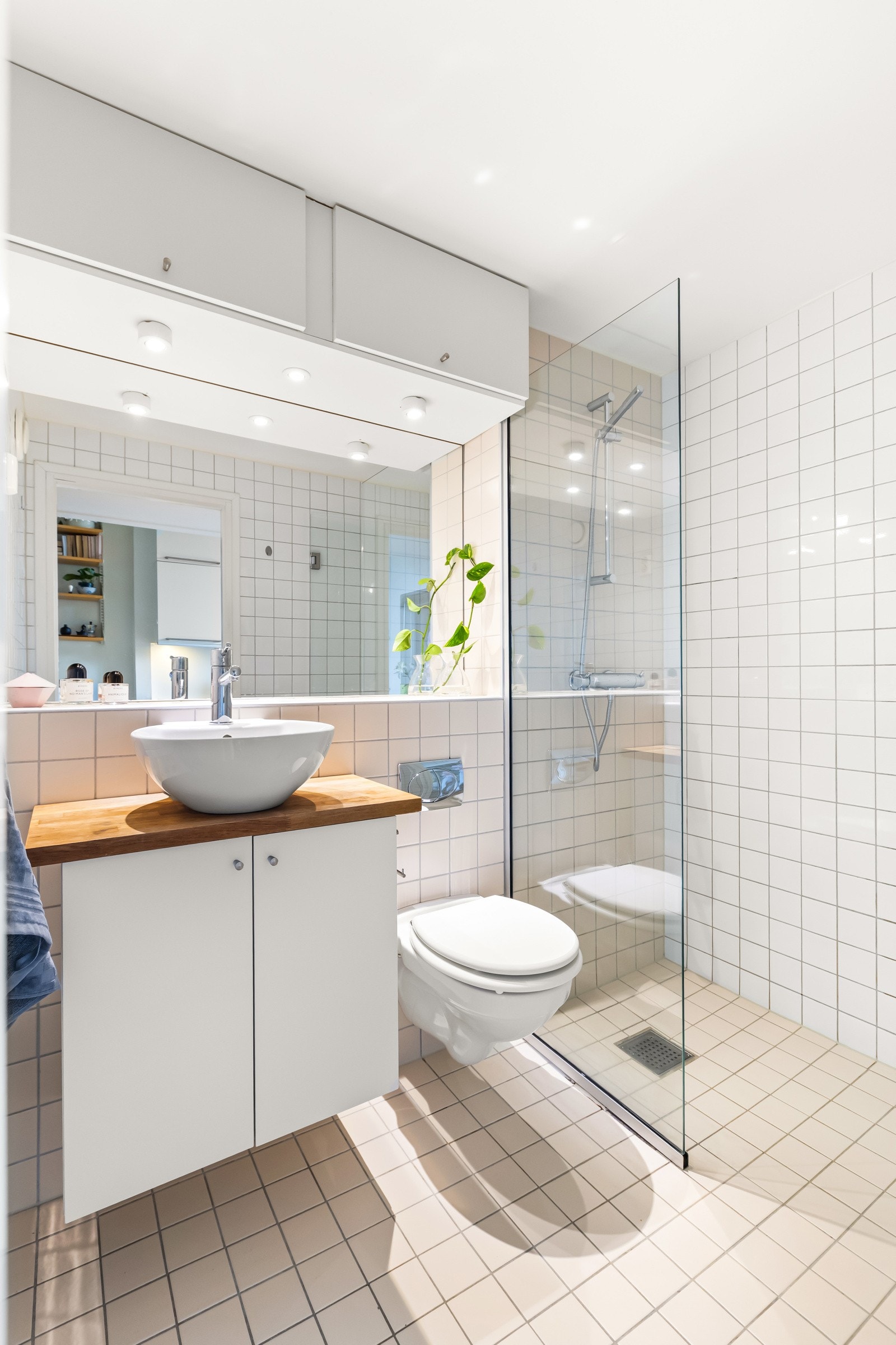 Stilrent baderom fra byggeår 2006/07. Badet består av veggmontert toalett, dusjsone med innfellbar dusjvegg, baderomsinnredning med skap og oppmontert servant på benkeplate i heltre. Balansert ventilasjon. Galleribilde