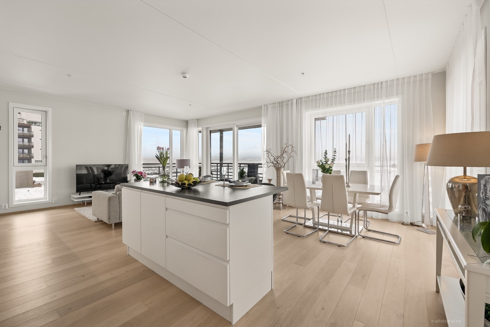 Stilren kjøkkeninnredning med overflater som består av hvite glatte fronter og benkeplate av laminat. Galleribilde