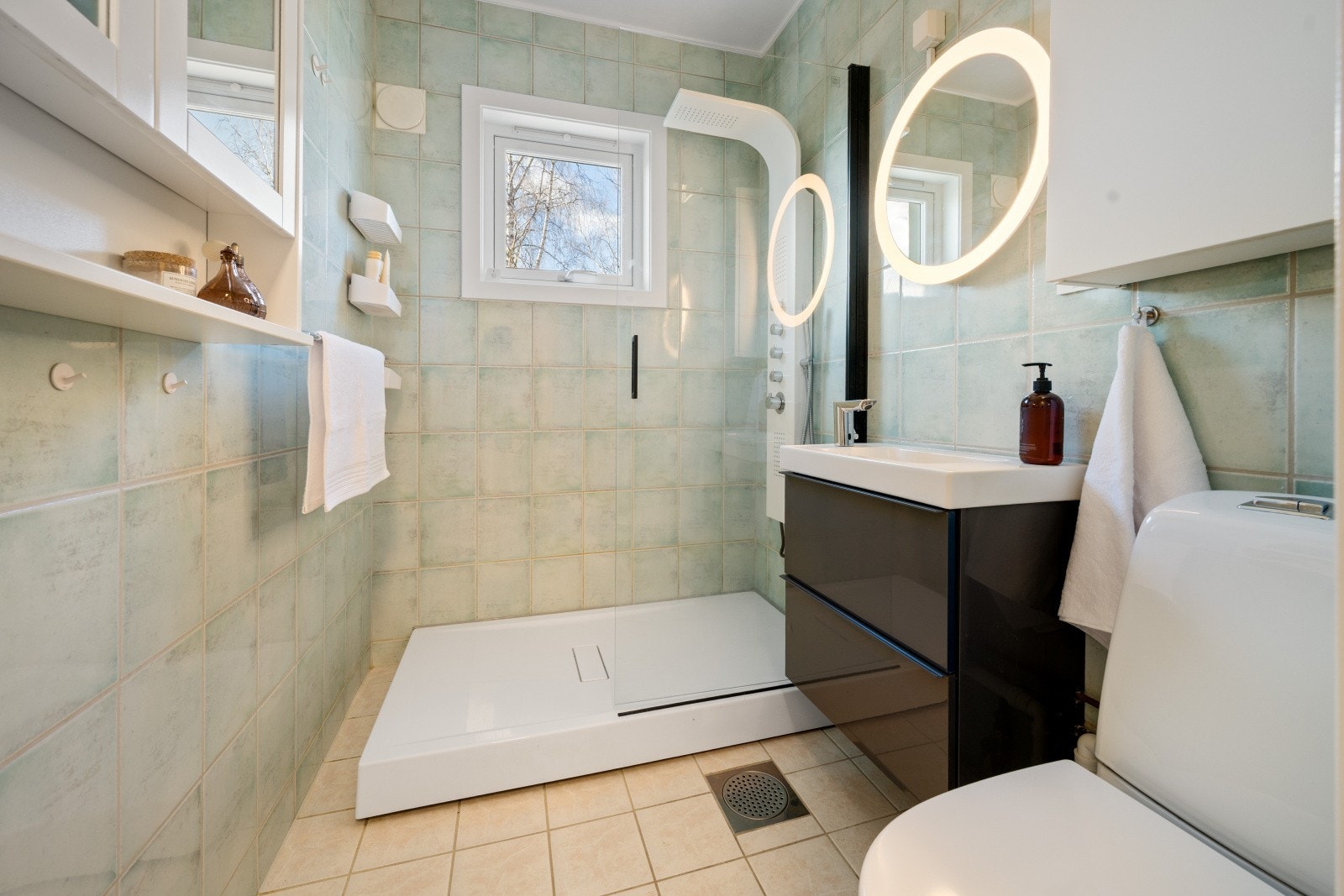 Badet har flislagt gulv med varmekabler, dusjkabinett og servantskap med heldekkende servant. Galleribilde