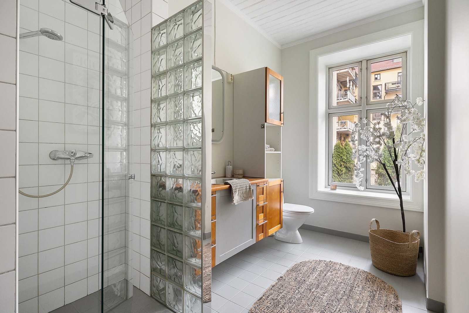 Baderomsinnredning bestående av benkeskap og veggskap med profilerte fronter. Vinduet gir fint lys inn på badet. Galleribilde