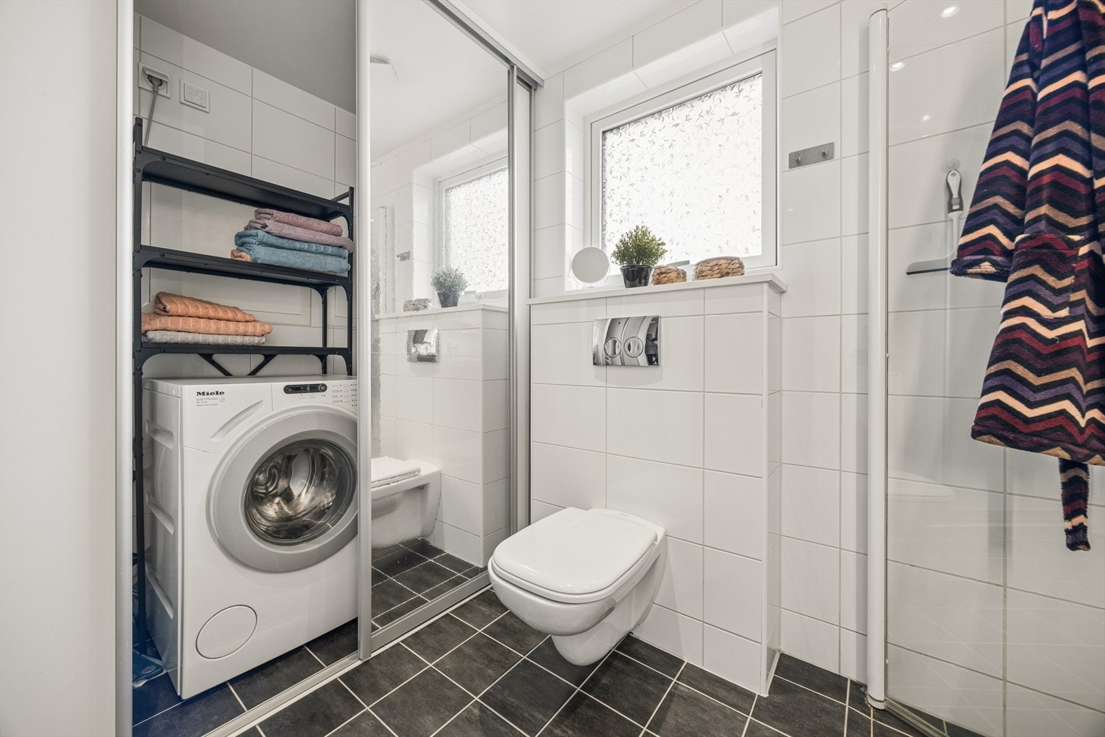 Badet har opplegg for vaskemaskin og huser boligens kombinerte anlegg for ventilasjon og varmepumpe. Galleribilde