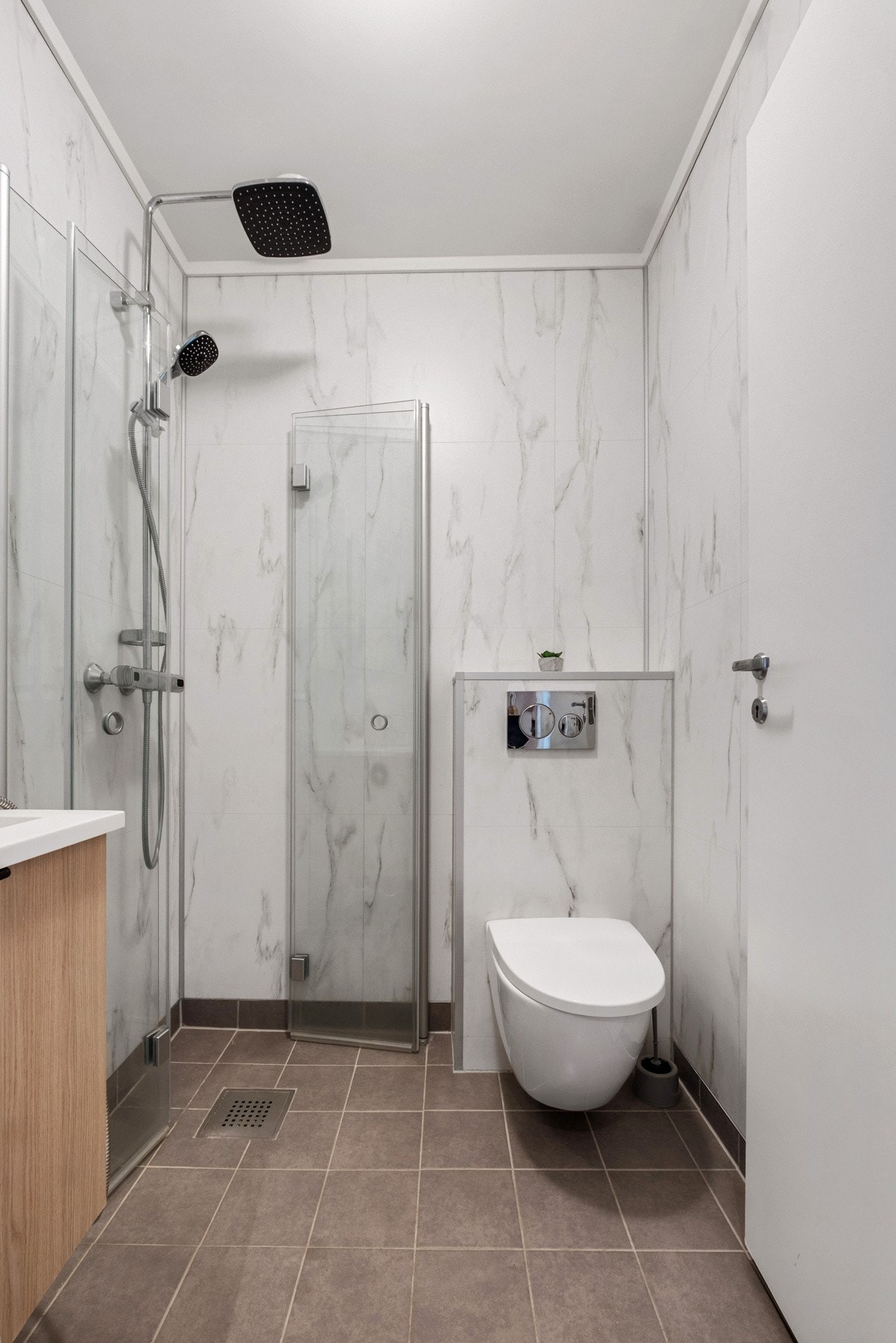 Badet har vegger med baderomsplater, flislagt gulv og elektriske varmekabler Galleribilde