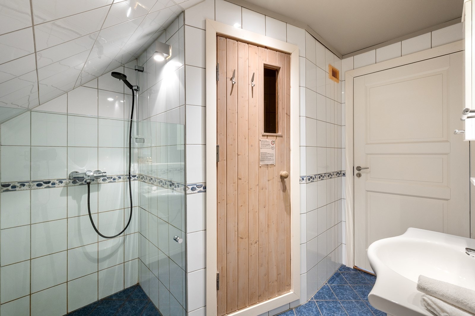 Badet er lyst og praktisk med keramiske fliser på gulv og vegger og malte flater i himling med innfelte spotter. Galleribilde