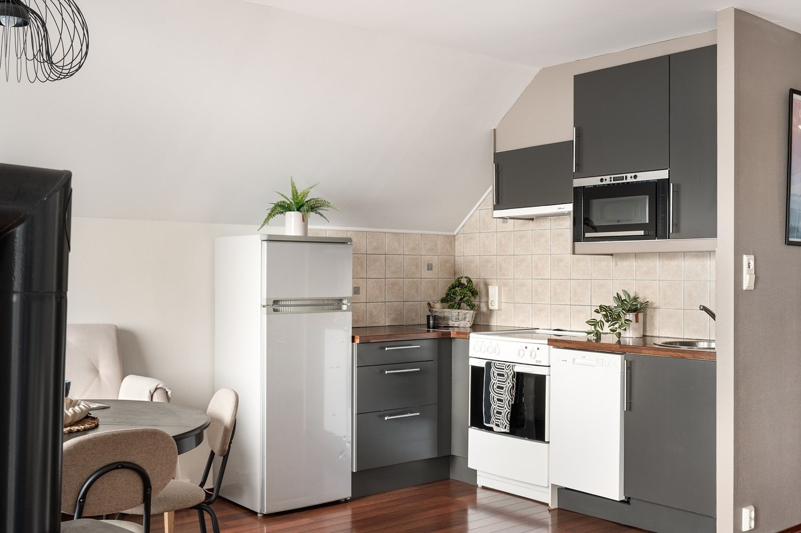 Kjøkkeninnredning fra IKEA med glatte fronter, benkeplate i laminat og nedfelt stålvask med ett-greps blandebatteri. Fliser over benkeplate og
belysning/stikk under overskap. Galleribilde