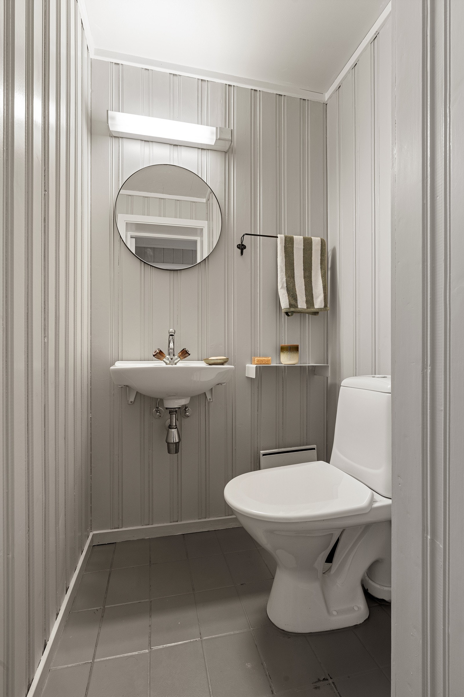 Toalettrom med fliser på gulv, wc og servant