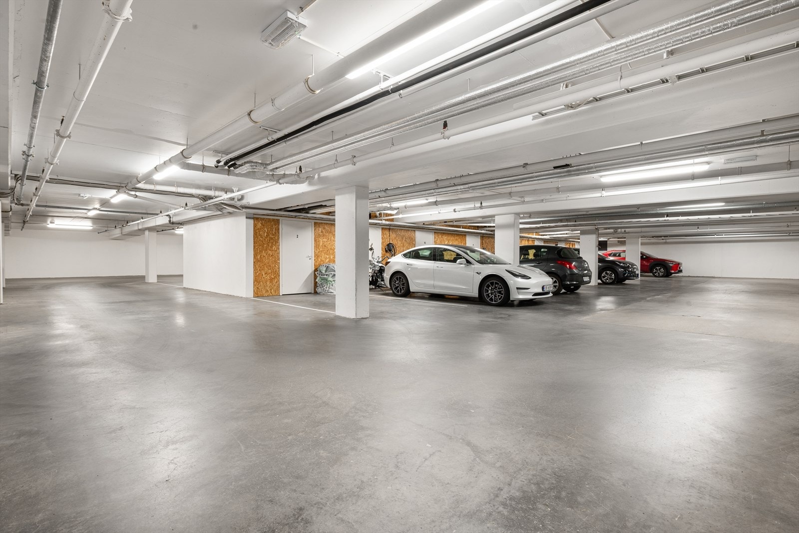 Garasjen i kjelleren er oppvarmet og gir trygg og lun parkering, skjermet for vær og vind. Elektronisk portåpner sørger for ekstra sikkerhet. Hver leilighet har egen bod.
Parkeringsplassen har plass til stor bil og den har egen ny elbillader. Galleribilde