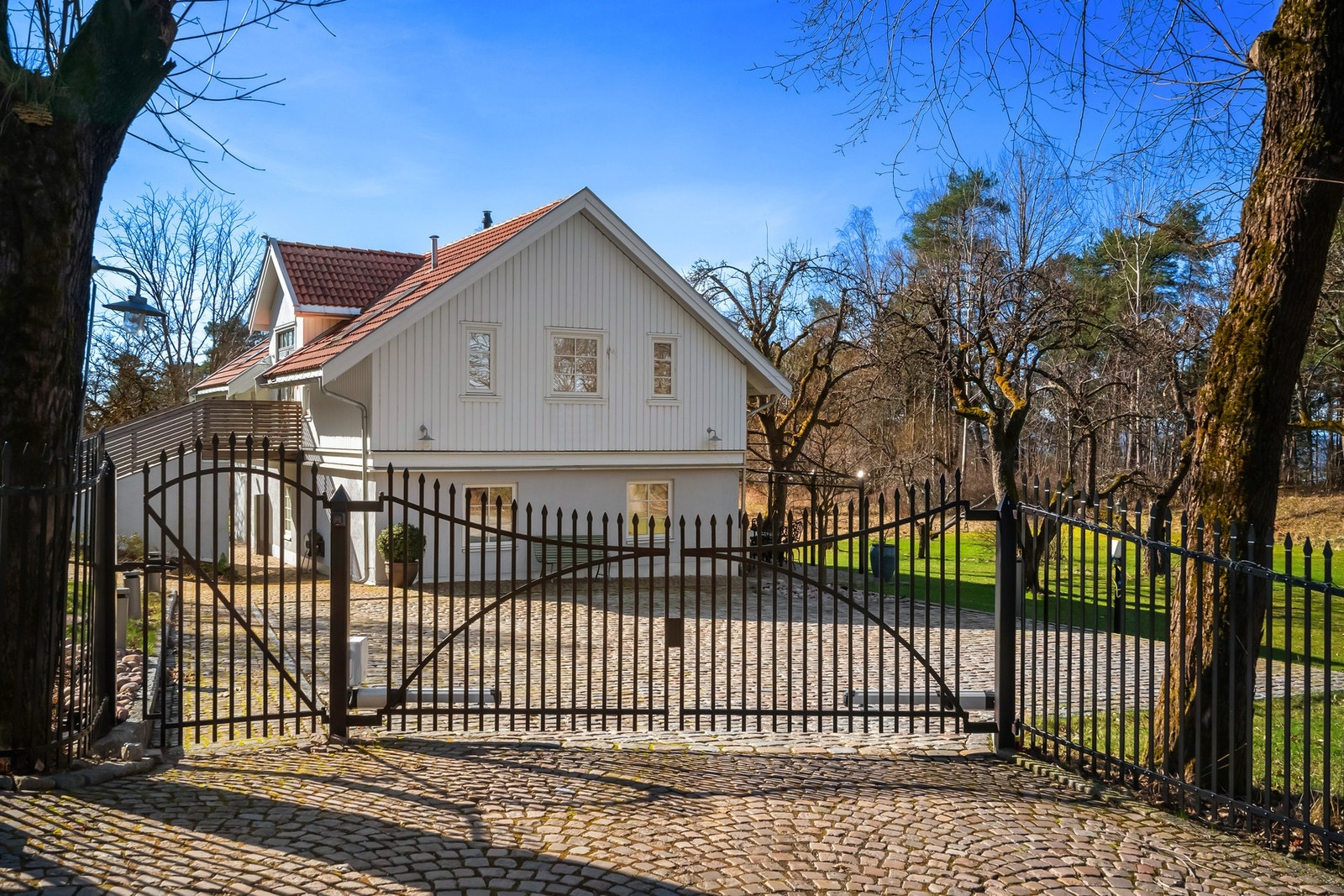 Elegant opparbeidet gårdsplass med bl.a. elektrisk smijernsport og gårdsplass belagt med brostein i rød granitt Galleribilde