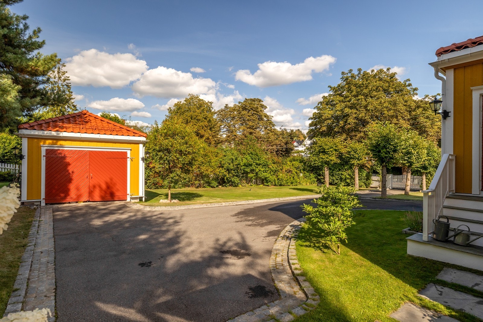 Stor asfaltert gårdsplass med plass til flere biler. Garasjen er i dag brukt som lagring av sykler og div. men er romslig for en bil Galleribilde