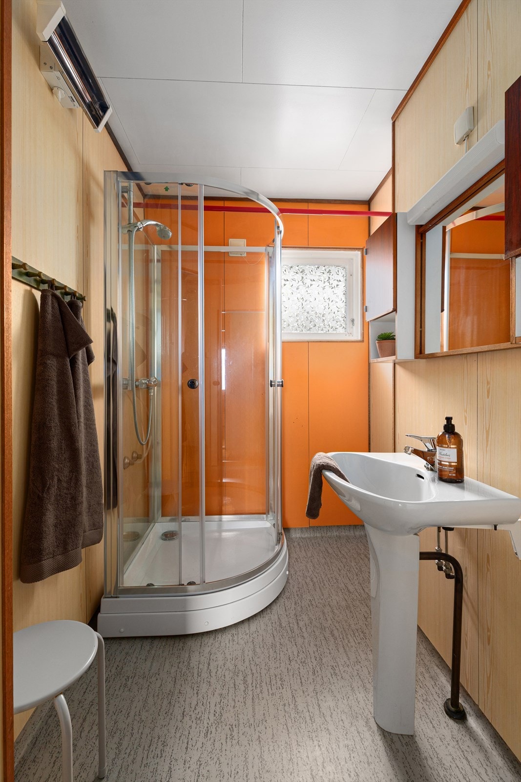 Badet er fra byggeåret og har belegg på gulv og våtromsplater på veggene. Rommet er innredet med dusjkabinett og enkel servant, samt veggskap, speil og lys. Galleribilde