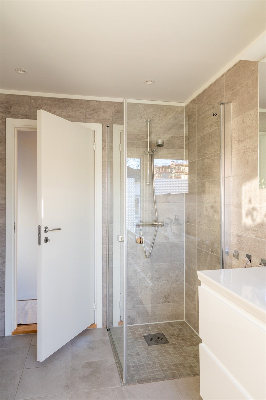 Badet er innredet med vegghengt klosett, servant nedfelt i innredning og dusjhjørne med svingbare glassdører. Det er elektrisk styrt vifte. Galleribilde