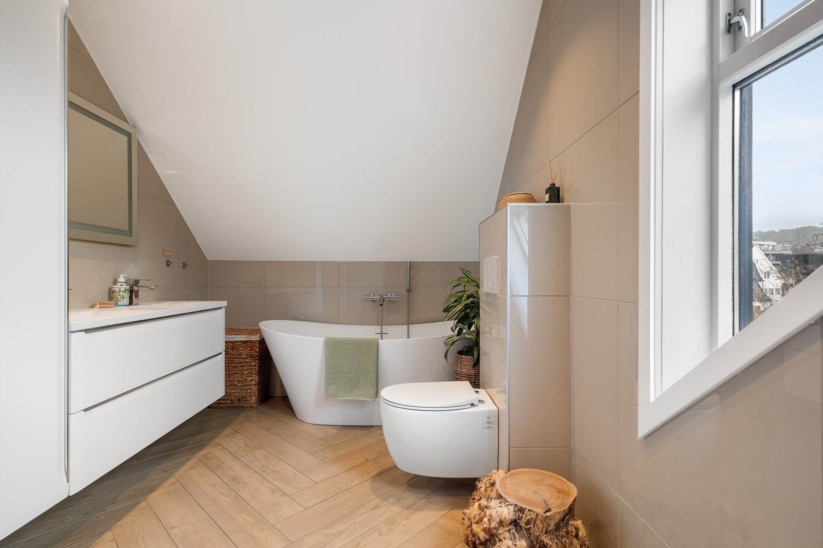 Badet byr på to servanter, et stilrent badekar, møbler og veggmontert toalett. Galleribilde