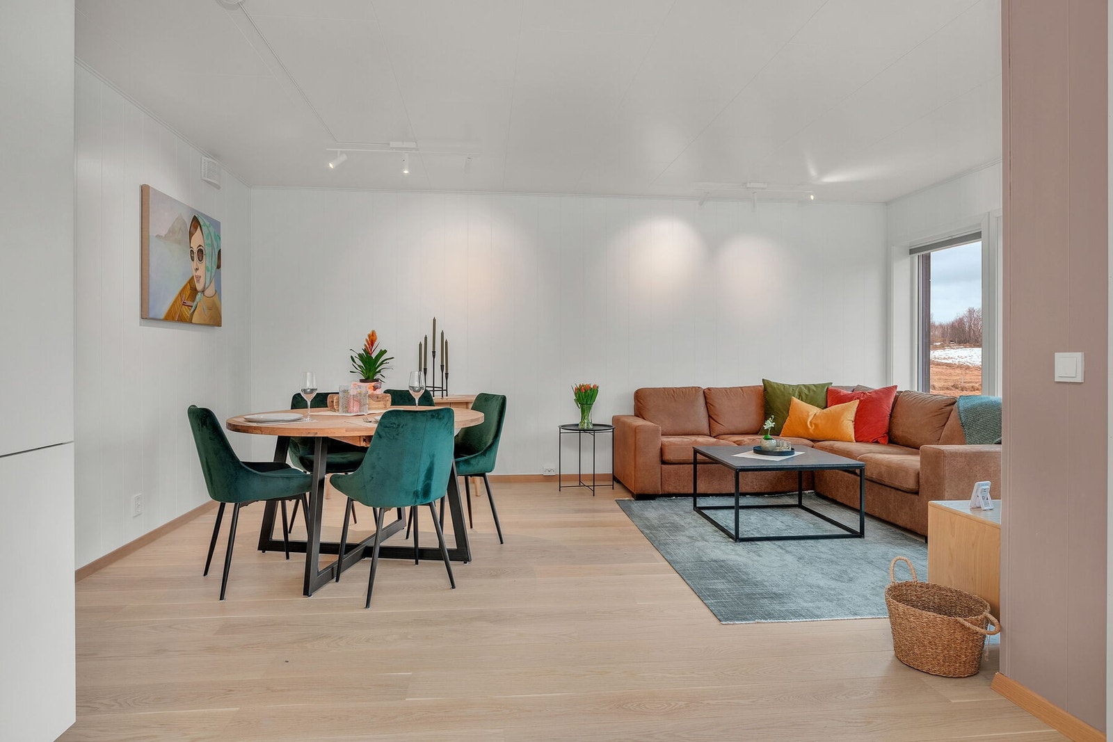 Oppholdsrommet har moderne overflater med parkett, lyse panelvegger og lyst tak, noe som gir et innbydende og helhetlig uttrykk. Galleribilde
