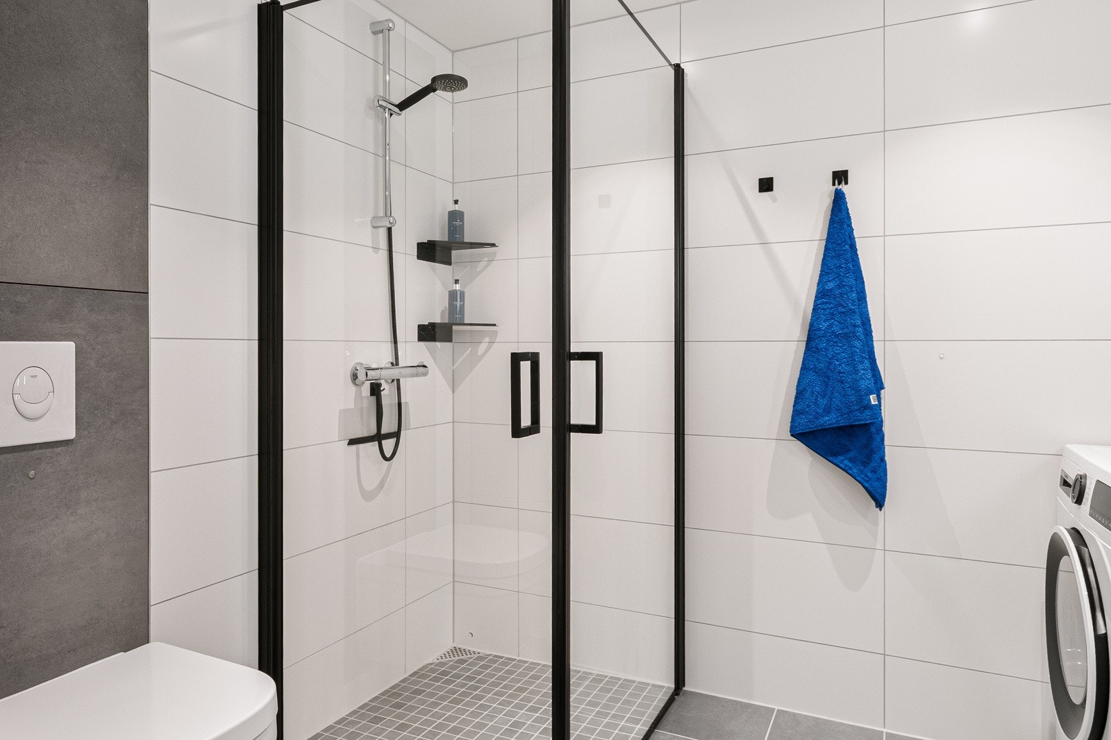 Badet er utstyrt med dusjnisje med innfellbare dører, vegghengt toalett og moderne innredning med slette fronter og heldekkende servant. Galleribilde