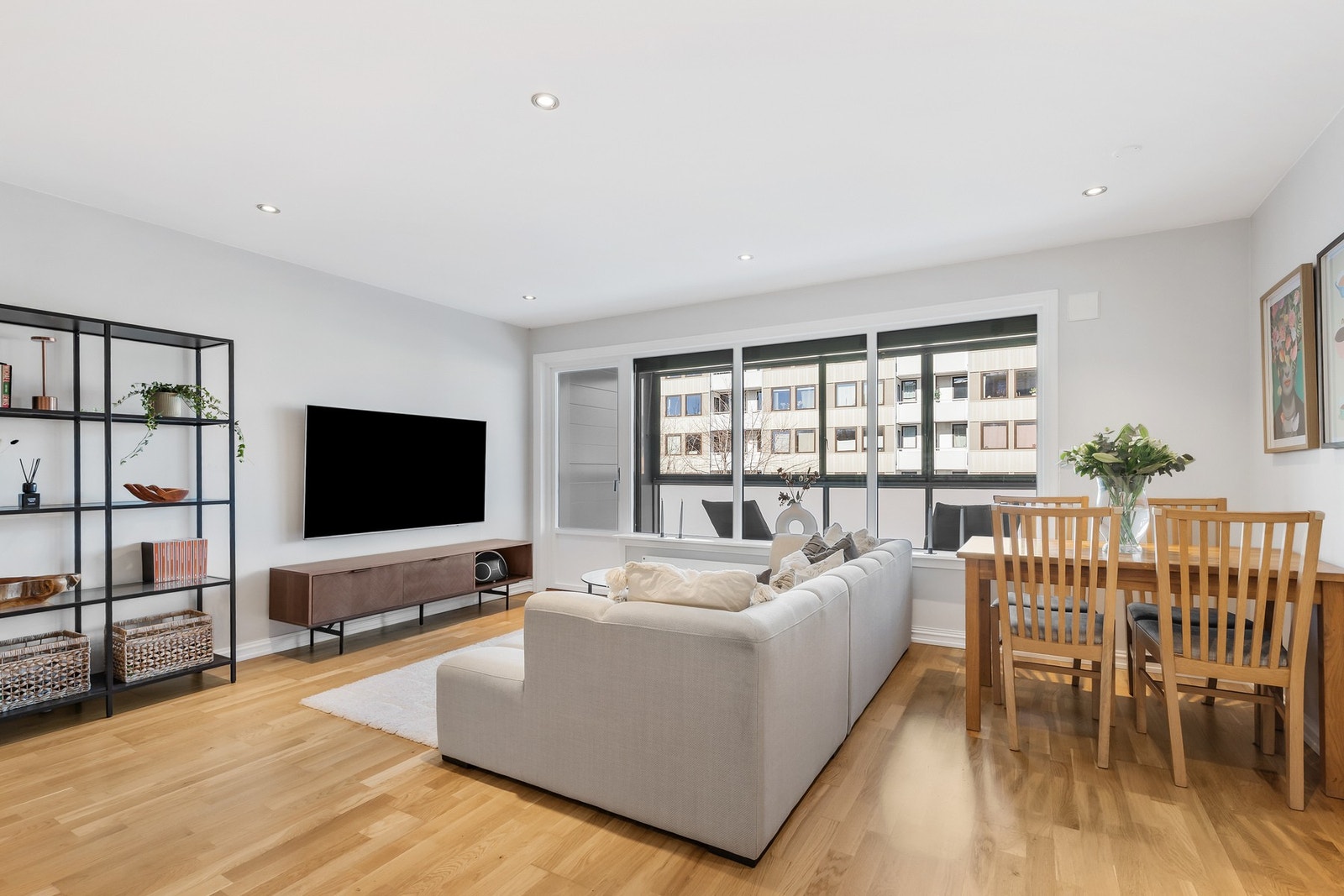 Innbydende stue med 3-stavs parkett på gulv, malte veggflater og nedsenket himling med downlights Galleribilde