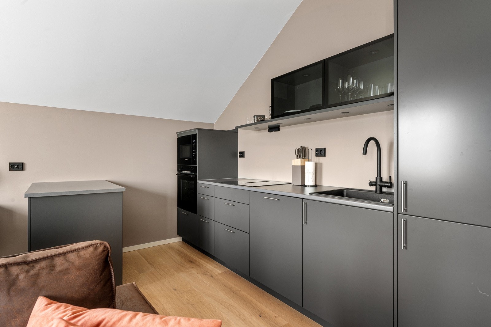 Delikat kjøkken med integrerte hvitevarer som kjøl, frys, oppvaskmaskin, induksjonstopp, stekovn og kjøkkenventilator.