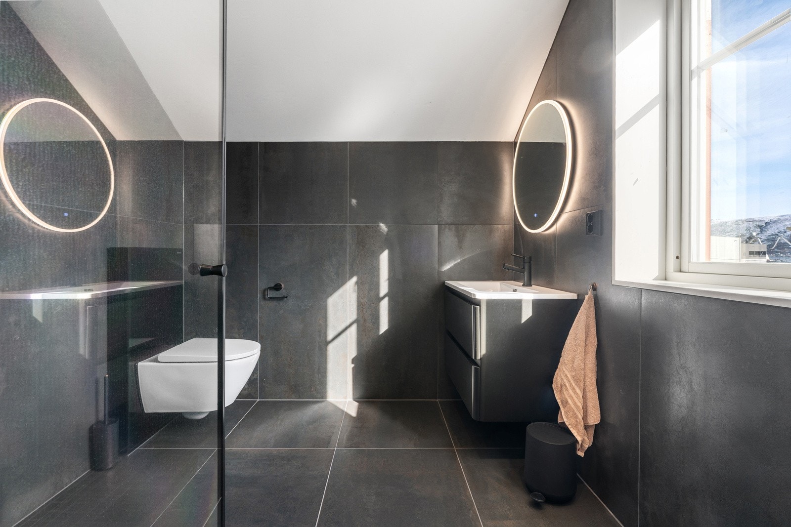 Vegghengt wc, innredning med skuffer og stor dusjnisje med glassdører.