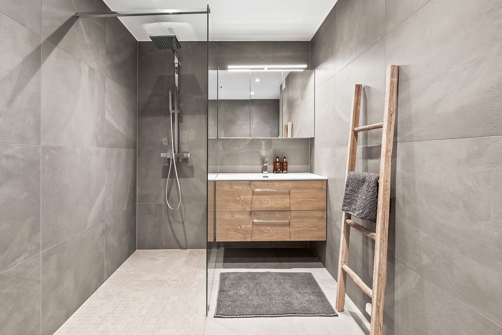 Badet er utstyrt med skuffeinnredning med nedfelt servant, speilskap, dusjhjørne med regnfallsdusj og hånddusj, samt vegghengt toalett. Galleribilde