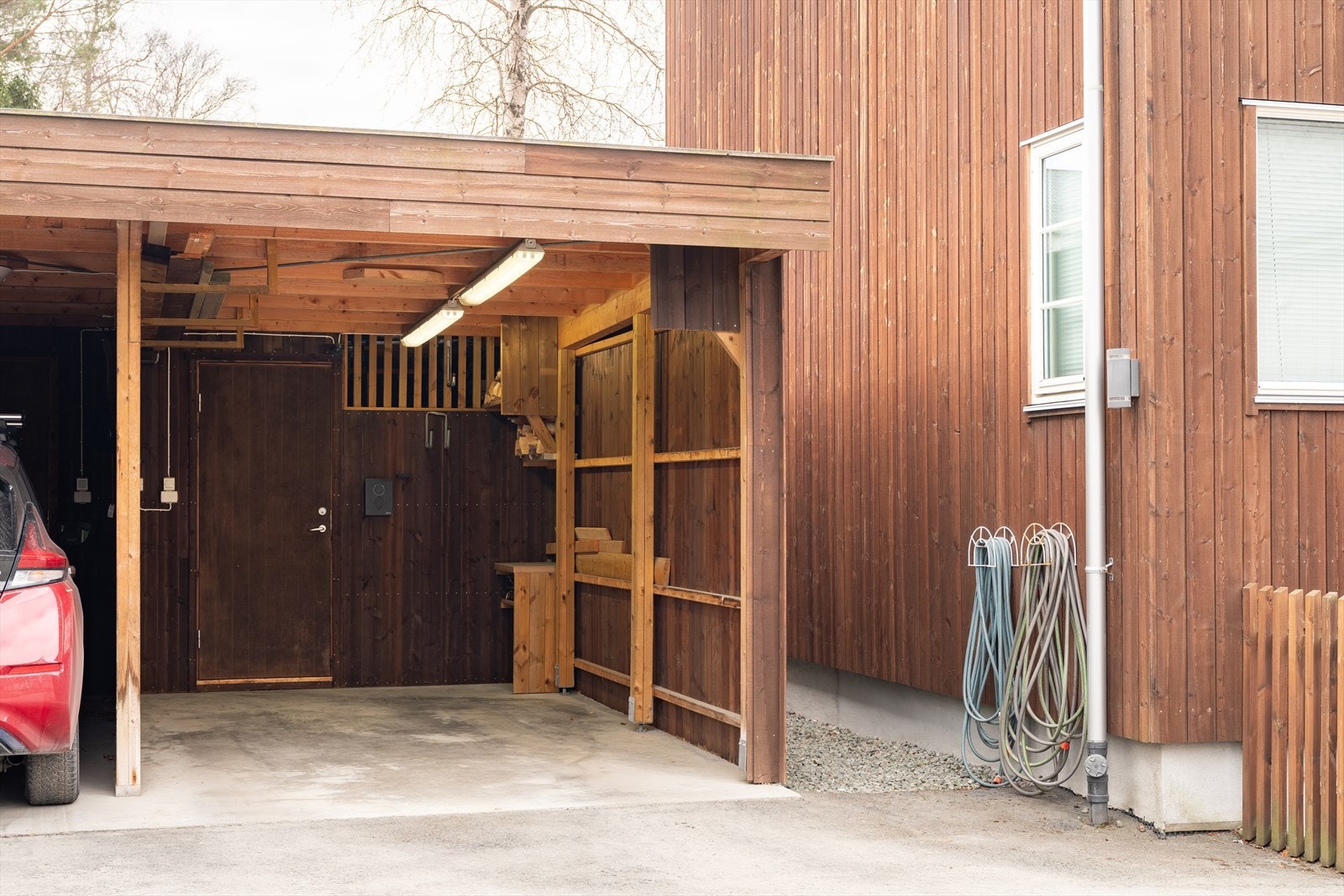 Boligen har parkeringsplass i carport med elbillader, hvor ekstern bod er i bakkant. Galleribilde