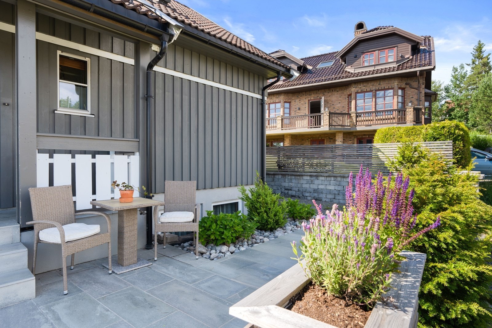Utenfor inngangsdøren til hoveddelen er det plass til å sette sittegruppe, og området er pent opparbeidet med blomsterbed og busker. Galleribilde