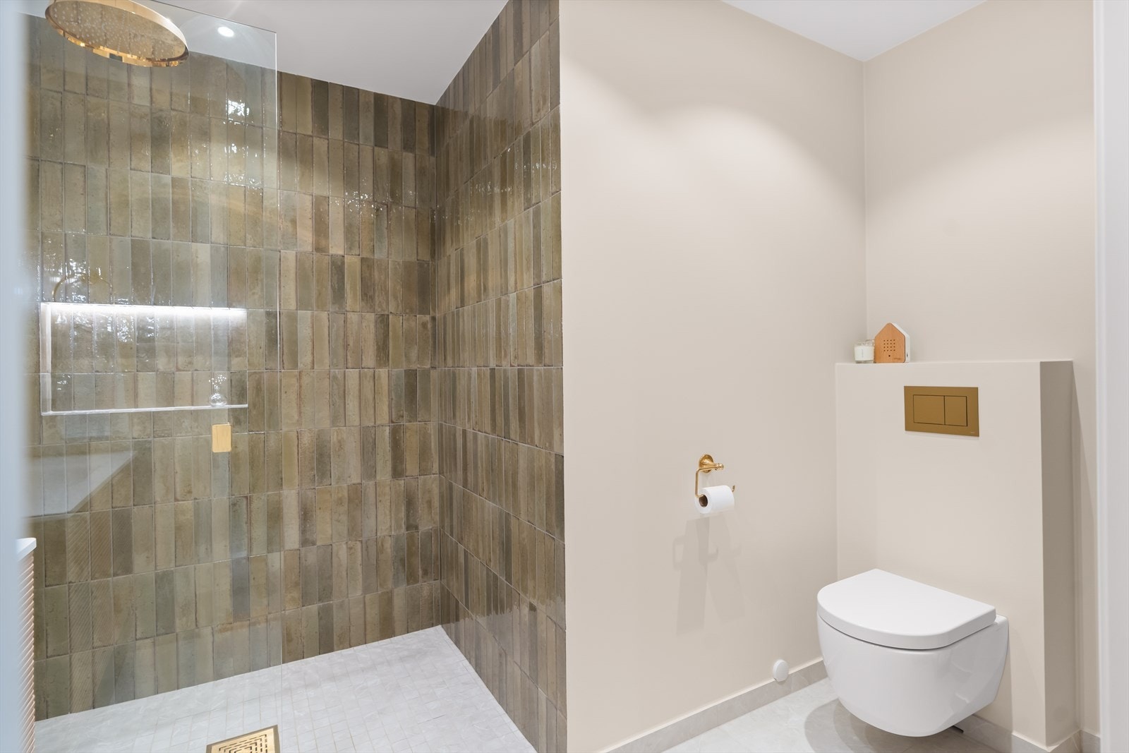 Videre rommer badet et vegghengt toalett, samt romslig dusjhjørne med glassfelt, utstyrt med regnfallsdusj, håndholdt dusj og termostatstyrt blandebatteri. Galleribilde