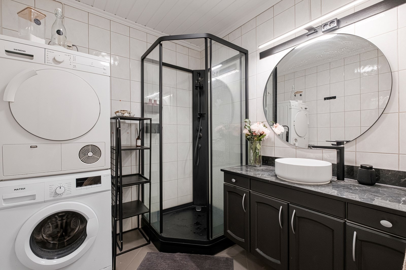 Det romslige badet er utstyrt med med nedfelt servant, toalett, dusjvegger/hjørne og opplegg for vaskemaskin Galleribilde
