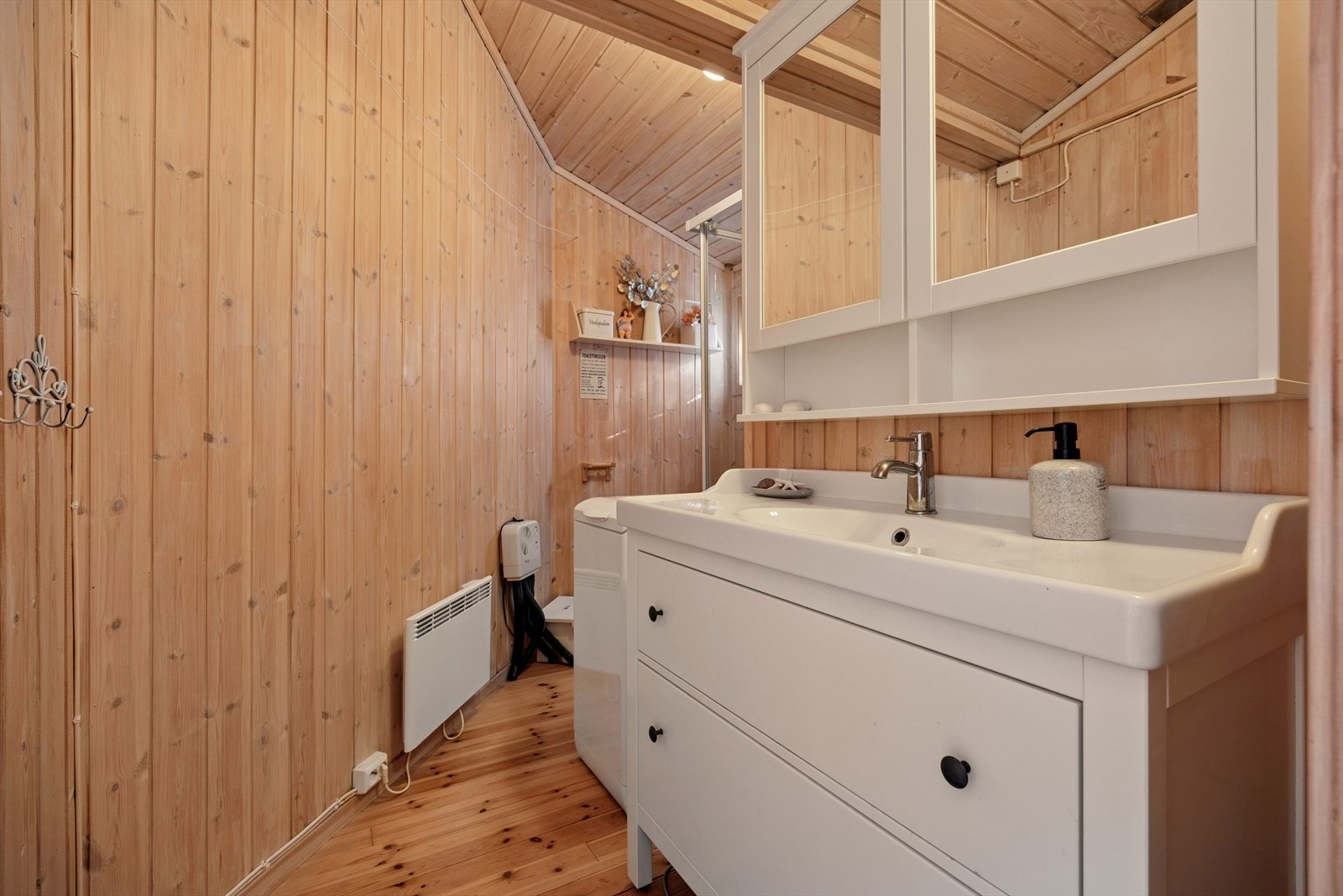 Bad/vaskerom er fra byggeår og påbygget i 2000. Gulvet er av tre og panel på veggene. Rommet har innredning med nedfelt servant, vaskemaskin, toalett og dusjkabinett. Panelovn som oppvarming. Det er ingen ventilering. Galleribilde