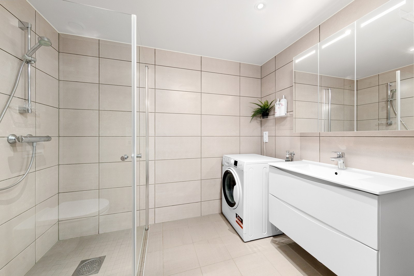 Badet er stilrent og fullt flislagt med en elektrisk gulvvarme som gir ekstra komfort. Galleribilde
