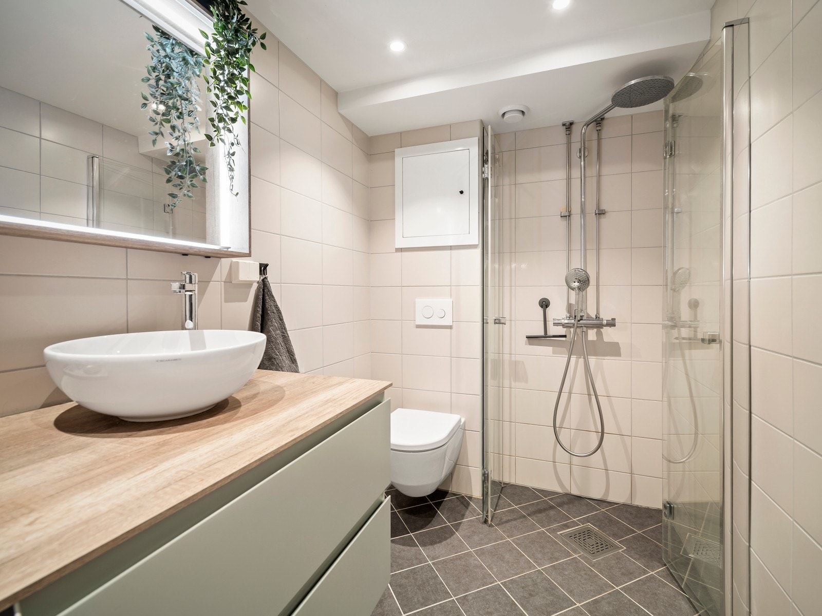 Det er elektriske varmekabler i gulvet. Badet er innredet med baderomsinnredning med nedfelt servant, veggmontert toalett, dusjhjørne med dusjvegger og opplegg for vaskemaskin. Det er naturlig ventilering i rommet. Galleribilde