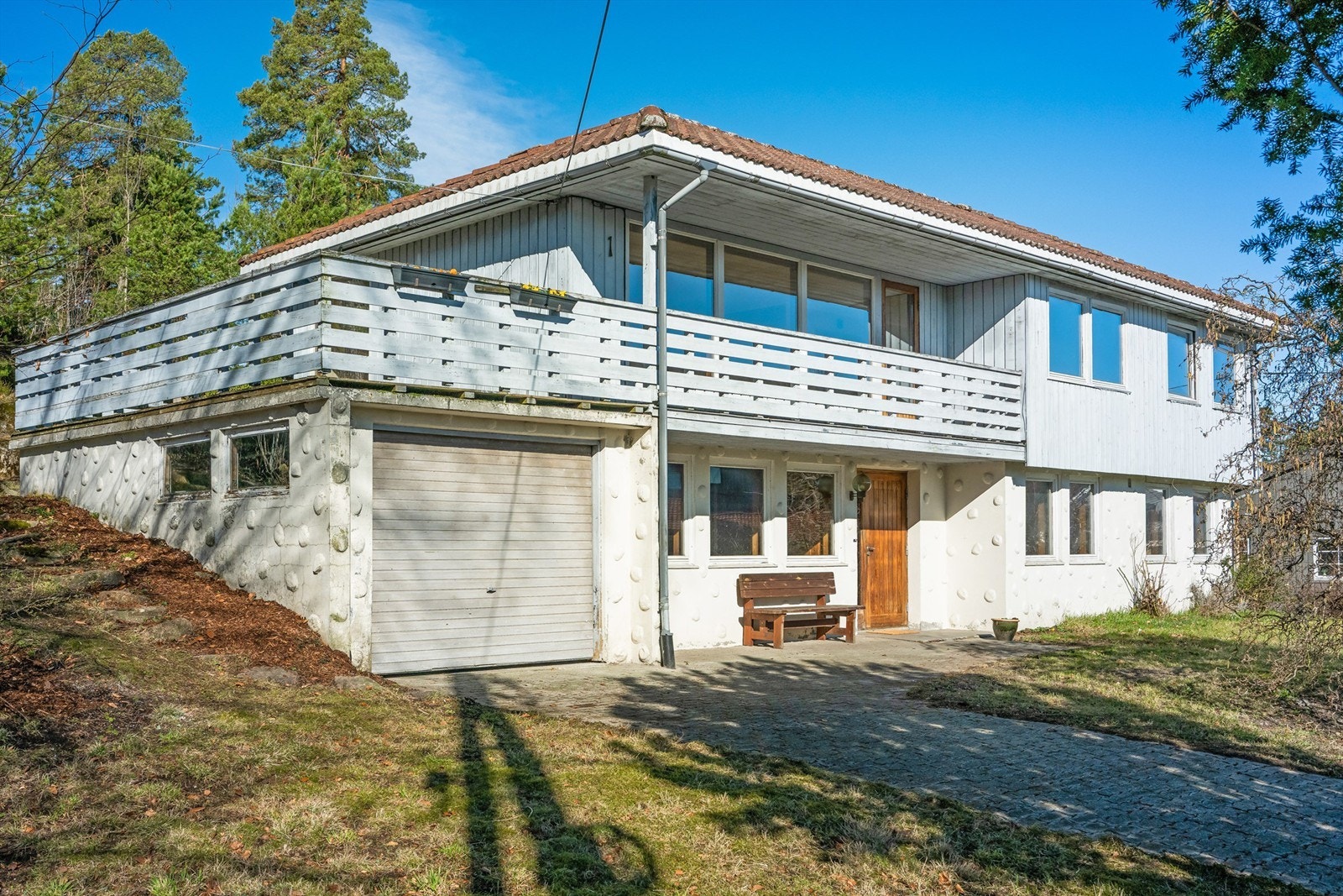 Fasaden har stående bordkledning og grunnmur i lettklinkerblokker, typisk for byggeåret 1974. Galleribilde