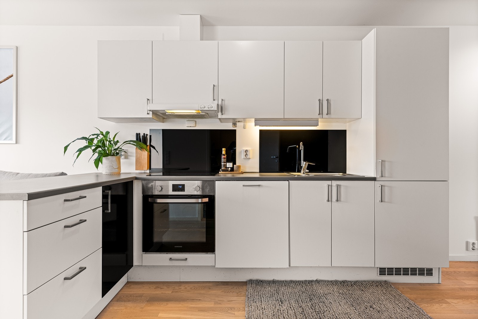 Kjøkkenet har en moderne innredning fra Sigdal med hvite, glatte fronter og laminat benkeplate. Galleribilde