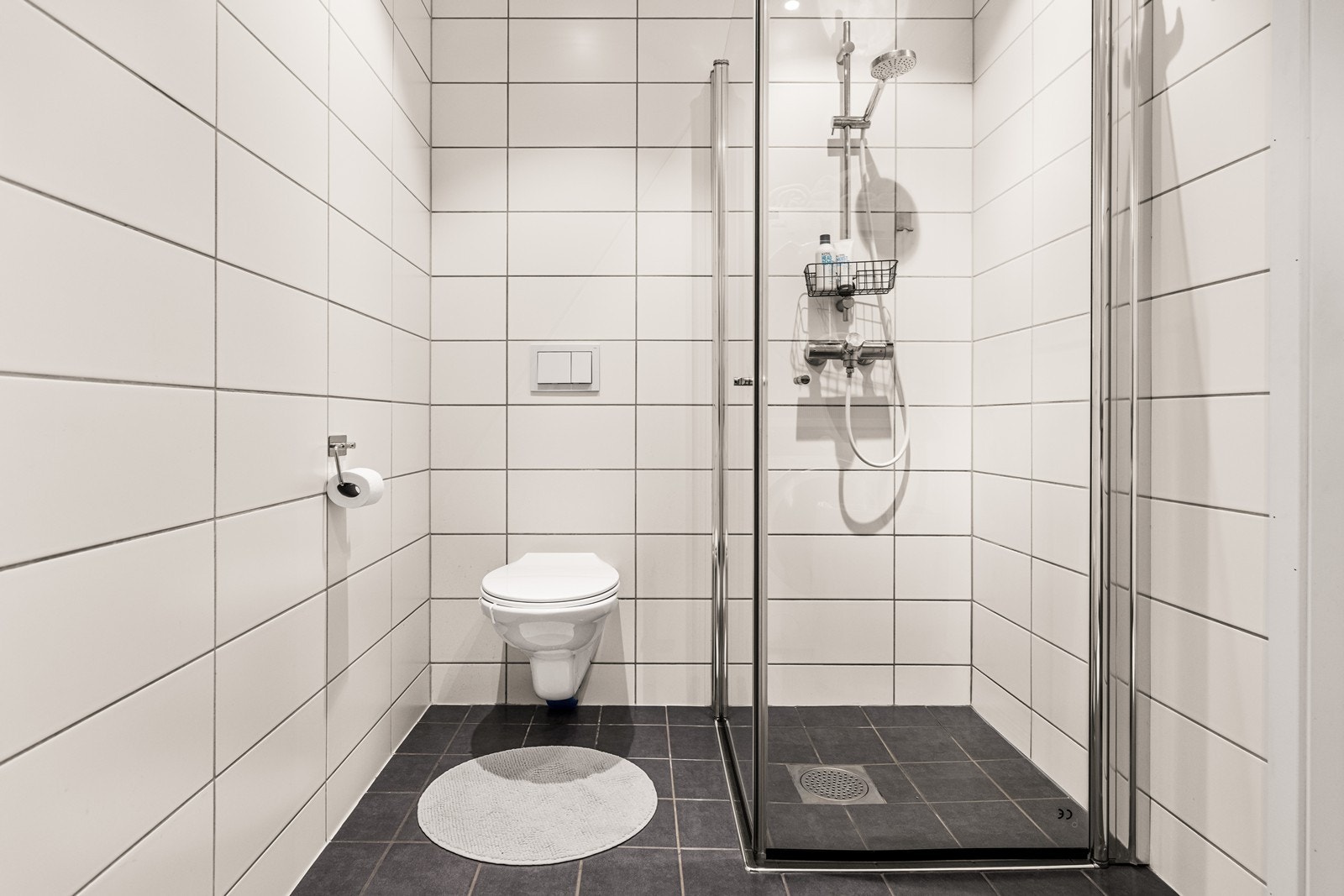 Badet er utstyrt med veggmontert toalett og et romslig dusjhjørne. Galleribilde