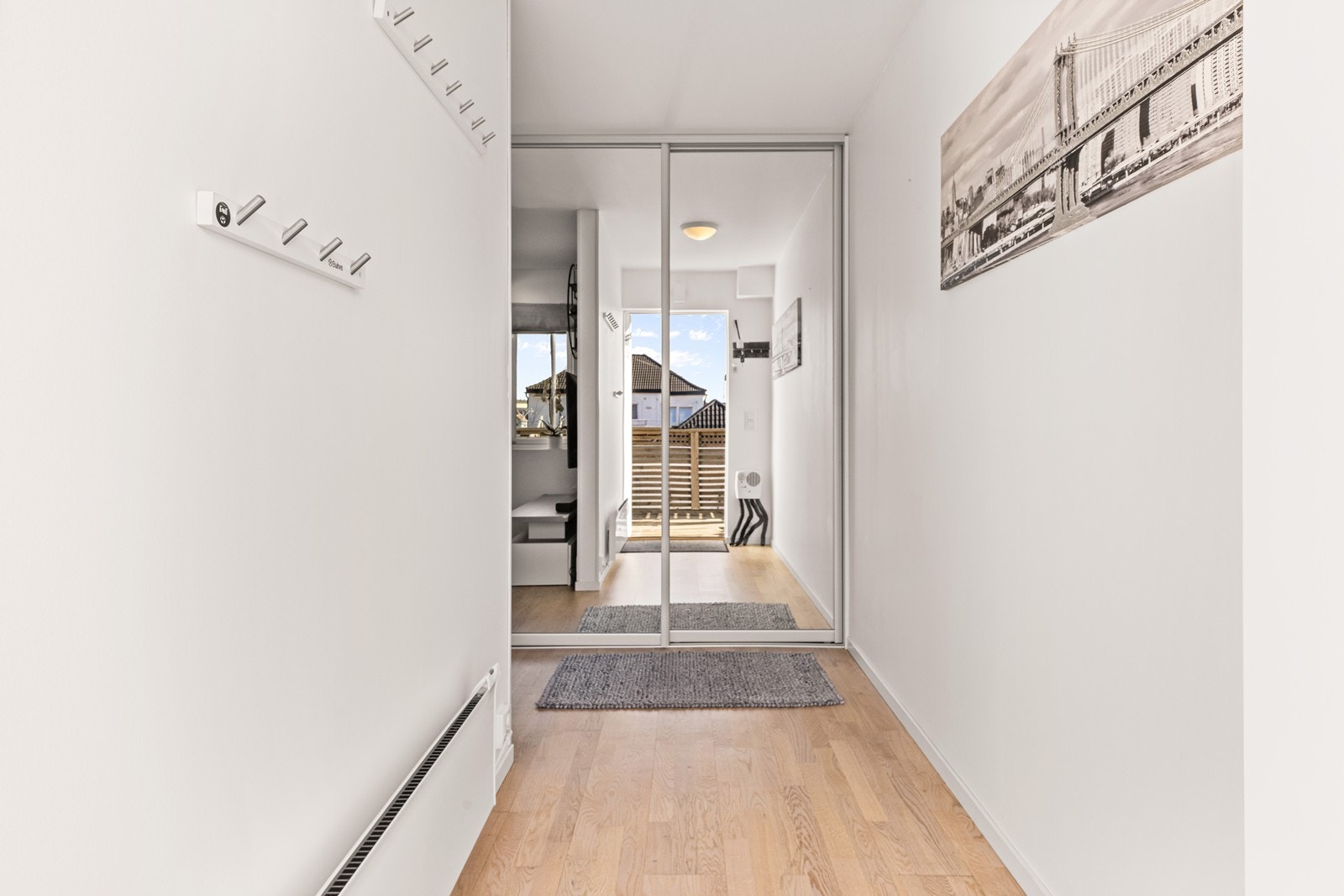 En lys entré ønsker velkommen inn. Herfra er det enkel tilgang til alle rom. Her er det også montert skyvedørsgarderobe for praktisk lagring. Galleribilde
