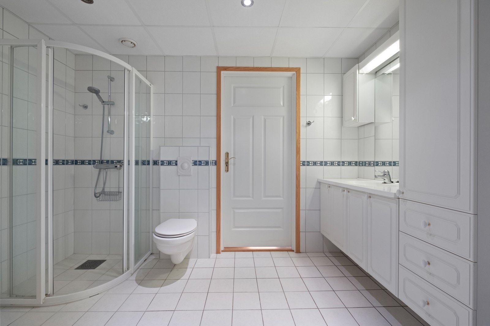 Badet er utstyrt med dusjhjørne, vegghengt wc og opplegg for vaskemaskin. Galleribilde